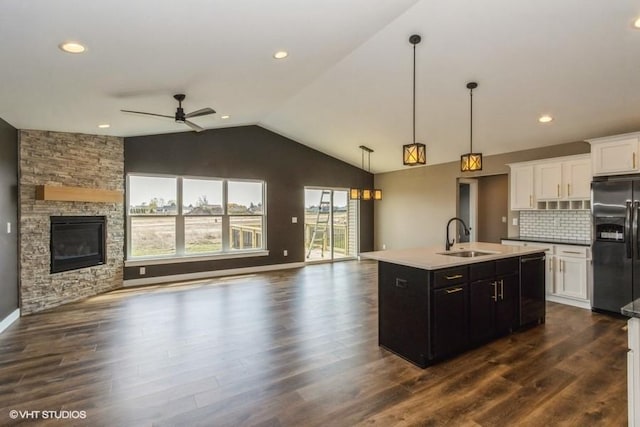 kitchen featuring sink, white cabinetry, stainless steel fridge with ice dispenser, dishwasher, and an island with sink