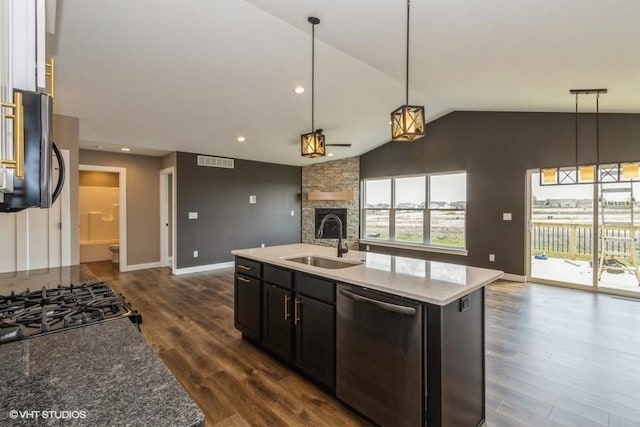 kitchen with an island with sink, dishwasher, sink, and hanging light fixtures