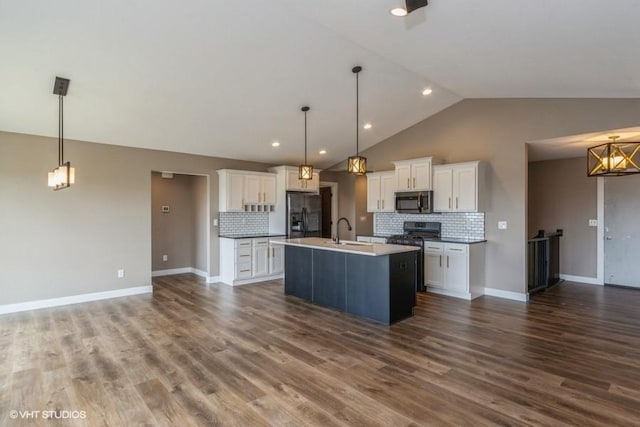 kitchen with appliances with stainless steel finishes, decorative light fixtures, a kitchen island with sink, and white cabinets