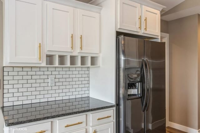 kitchen with stainless steel fridge with ice dispenser, decorative backsplash, dark stone counters, and white cabinets