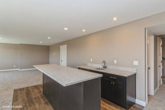 kitchen with light stone counters, sink, wood-type flooring, and a kitchen island