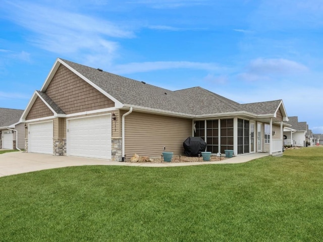 exterior space featuring a garage, a sunroom, and a lawn