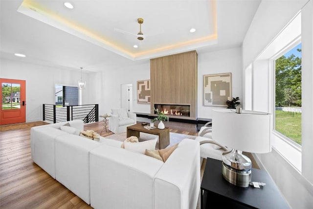 living room featuring a large fireplace, light hardwood / wood-style flooring, and a raised ceiling