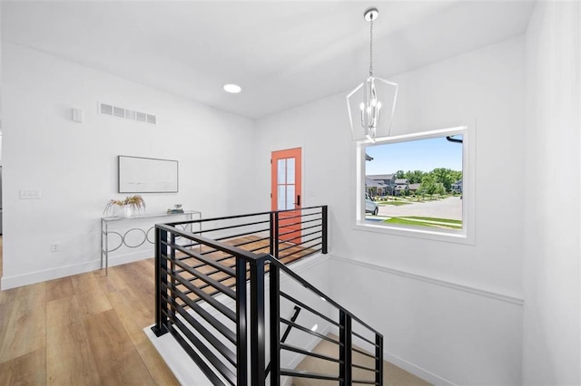 staircase with hardwood / wood-style flooring and an inviting chandelier