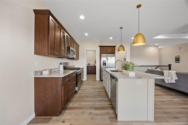 kitchen featuring appliances with stainless steel finishes, sink, pendant lighting, and light stone counters