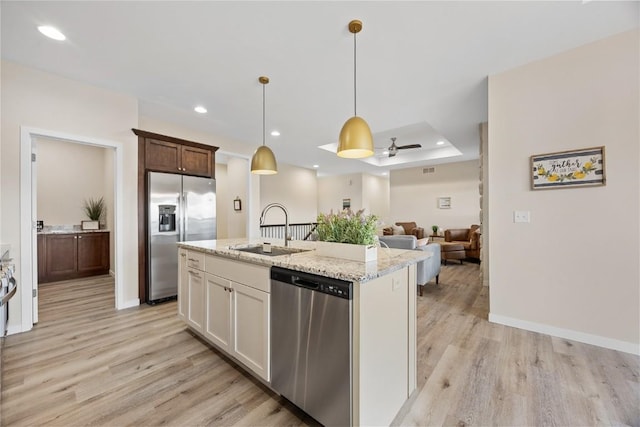 kitchen featuring sink, appliances with stainless steel finishes, dark brown cabinets, light stone counters, and a raised ceiling