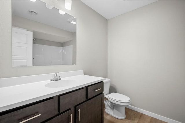 bathroom featuring walk in shower, hardwood / wood-style floors, vanity, and toilet