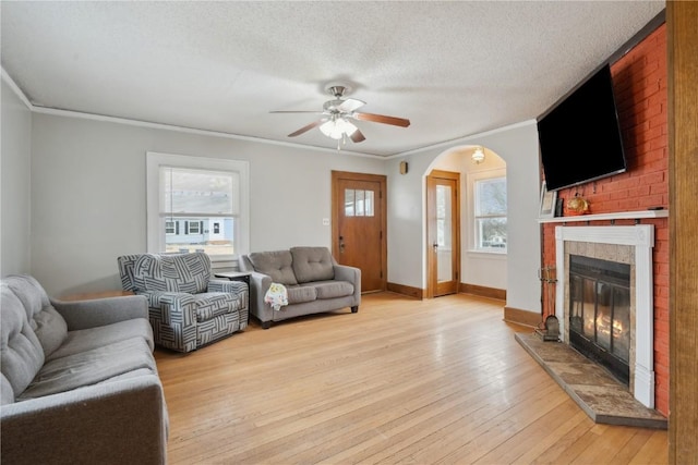 living room featuring crown molding, ceiling fan, light hardwood / wood-style flooring, and a textured ceiling