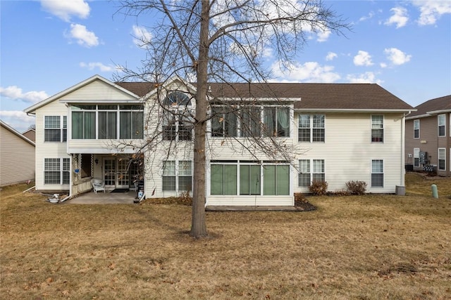 rear view of house featuring a lawn, a sunroom, and a patio