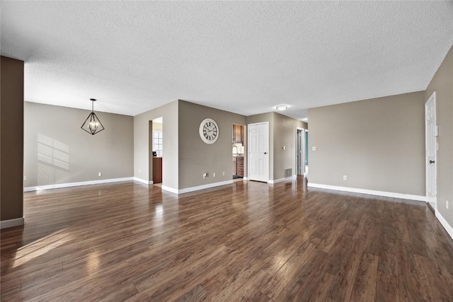 unfurnished living room featuring a chandelier, a textured ceiling, and dark hardwood / wood-style flooring