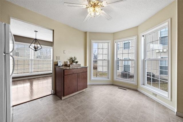 interior space featuring plenty of natural light, ceiling fan with notable chandelier, and a textured ceiling