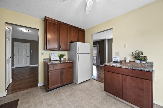 kitchen with white refrigerator, dark brown cabinets, ceiling fan, and a textured ceiling