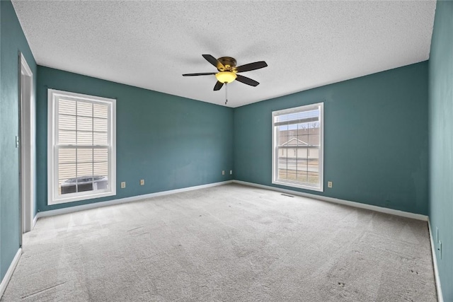 spare room featuring ceiling fan, light colored carpet, and a textured ceiling