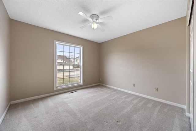 empty room featuring ceiling fan, light colored carpet, and a textured ceiling