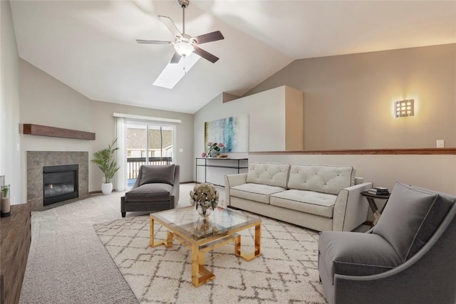 living room featuring ceiling fan, a fireplace, and vaulted ceiling with skylight