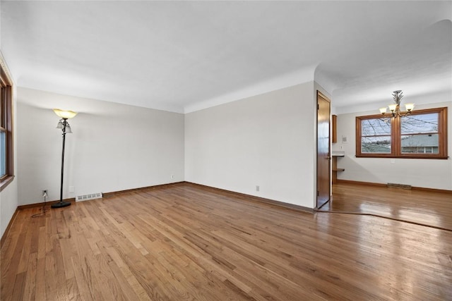 unfurnished living room featuring an inviting chandelier and light wood-type flooring