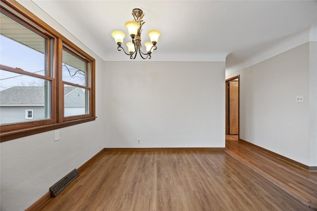 unfurnished room with wood-type flooring and a notable chandelier