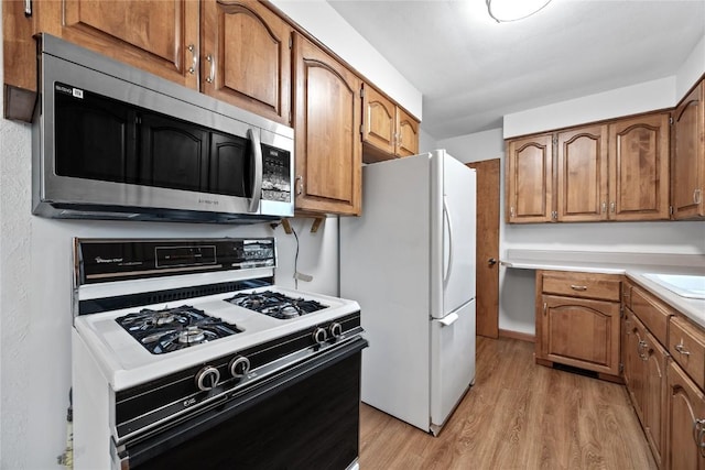 kitchen featuring white fridge, range with gas stovetop, and light wood-type flooring