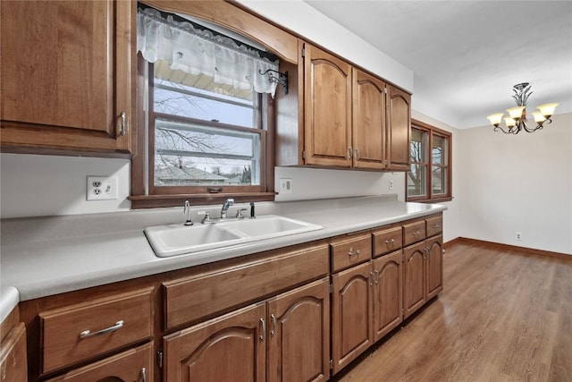 kitchen featuring sink, a chandelier, and light wood-type flooring