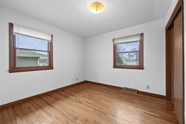 unfurnished bedroom with multiple windows, light hardwood / wood-style flooring, and a closet