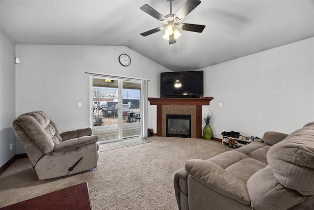 carpeted living room with ceiling fan, lofted ceiling, and a tiled fireplace