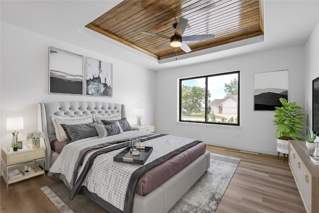 bedroom with a tray ceiling, wooden ceiling, ceiling fan, and light wood-type flooring