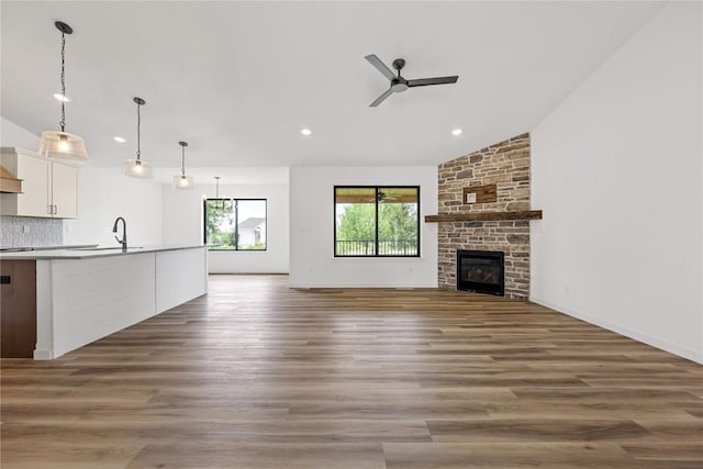 unfurnished living room featuring ceiling fan, lofted ceiling, dark wood-type flooring, and a fireplace