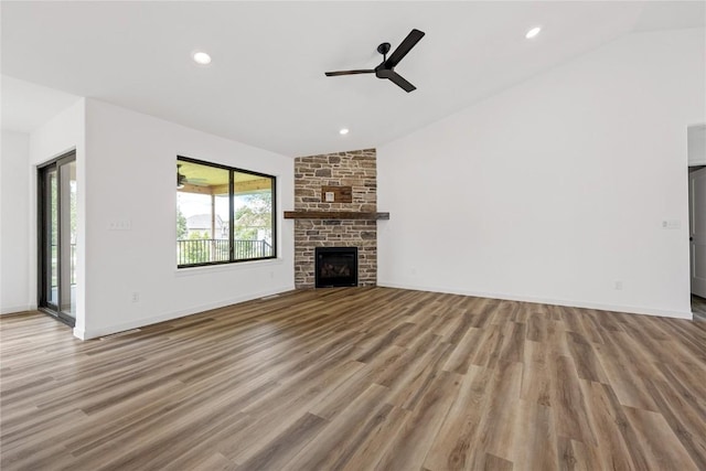 unfurnished living room featuring light hardwood / wood-style flooring, a stone fireplace, vaulted ceiling, and ceiling fan