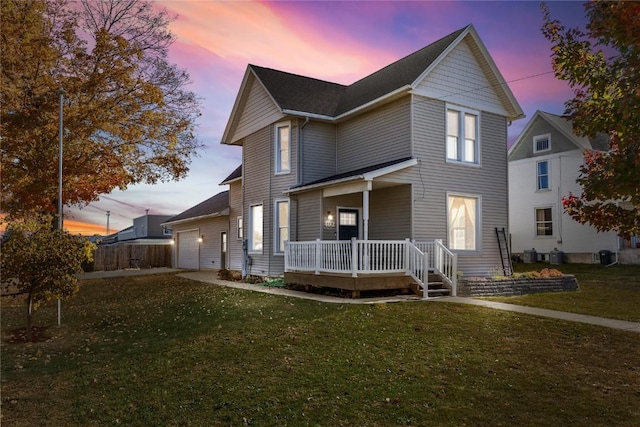 view of property featuring a garage, a porch, and a yard