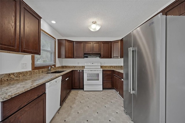 kitchen featuring sink, white appliances, dark brown cabinetry, light stone counters, and a textured ceiling