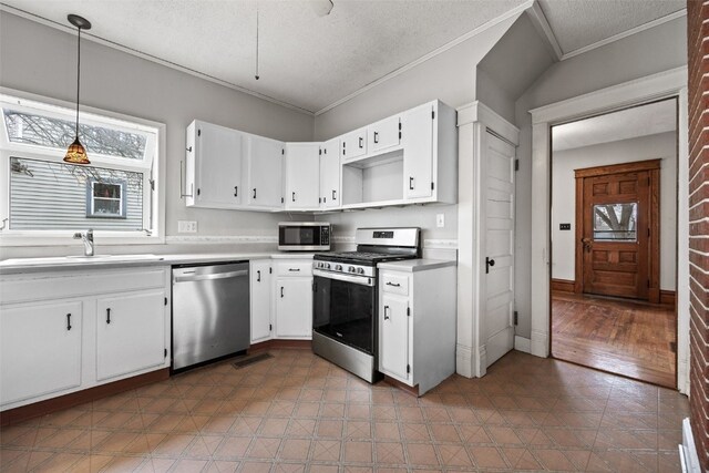 kitchen with appliances with stainless steel finishes, a wealth of natural light, decorative light fixtures, sink, and white cabinets