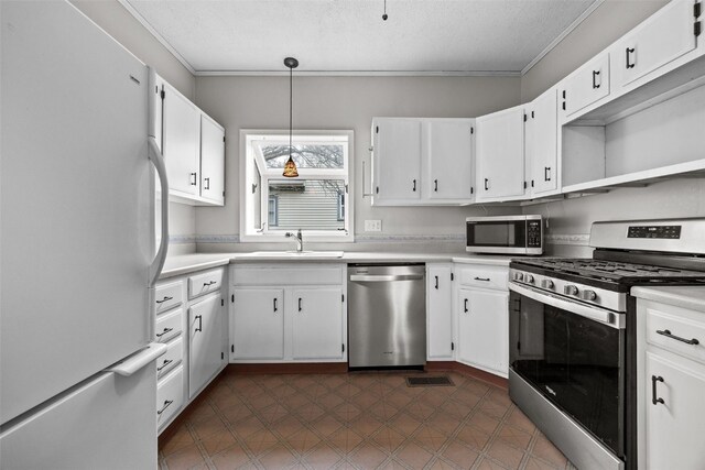 kitchen with pendant lighting, sink, appliances with stainless steel finishes, a textured ceiling, and white cabinets