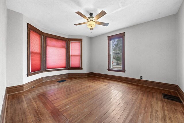 empty room featuring ceiling fan, wood-type flooring, and a textured ceiling