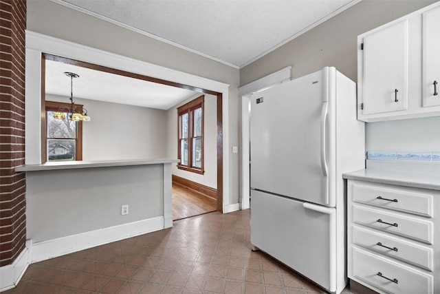 kitchen with hanging light fixtures, white fridge, a healthy amount of sunlight, and white cabinets