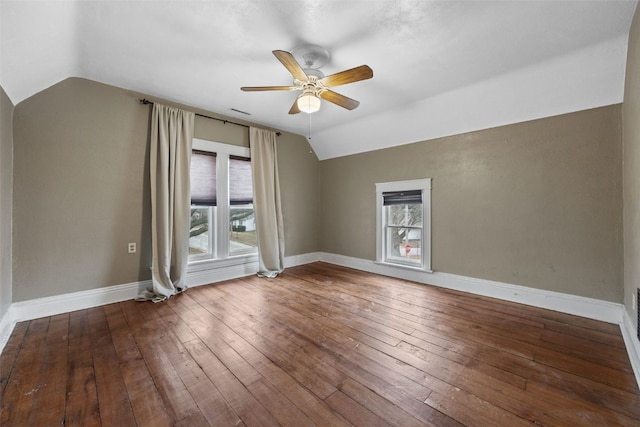 spare room featuring wood-type flooring, vaulted ceiling, and a wealth of natural light