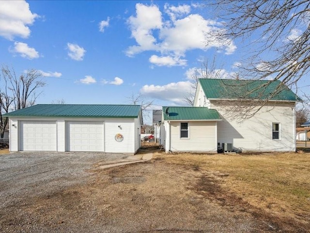 exterior space with a garage, central AC, an outbuilding, and a front lawn