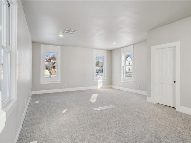 unfurnished room featuring light carpet and a wealth of natural light