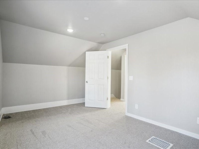 bonus room with lofted ceiling and light carpet