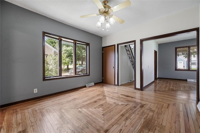 spare room featuring ceiling fan, a healthy amount of sunlight, and light parquet floors