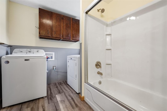 bathroom featuring hardwood / wood-style floors, enclosed tub / shower combo, and washer and dryer