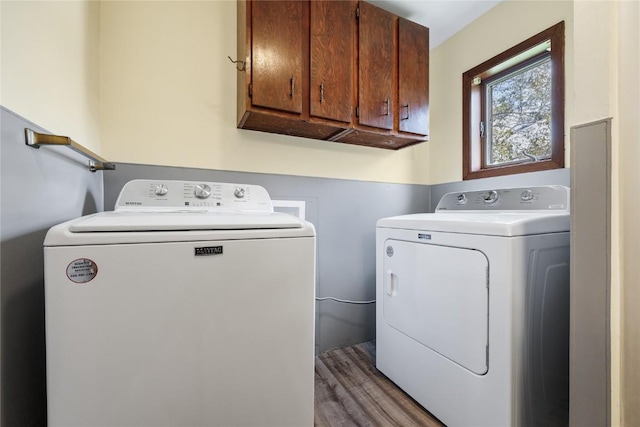 clothes washing area with cabinets, wood-type flooring, and washer and dryer