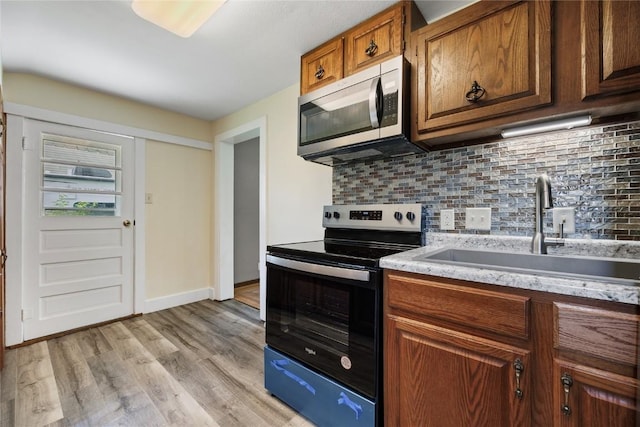 kitchen with range with electric cooktop, sink, decorative backsplash, and light wood-type flooring