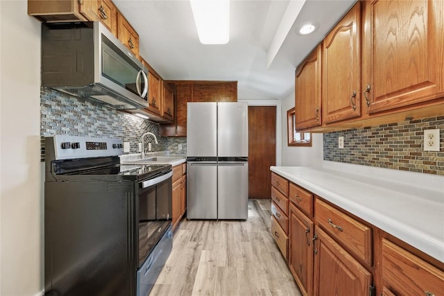 kitchen featuring tasteful backsplash, sink, light wood-type flooring, and appliances with stainless steel finishes