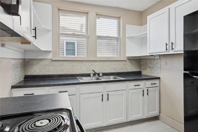 kitchen with black fridge, sink, white cabinets, and decorative backsplash