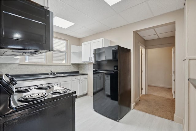 kitchen featuring sink, a paneled ceiling, tasteful backsplash, black appliances, and white cabinets