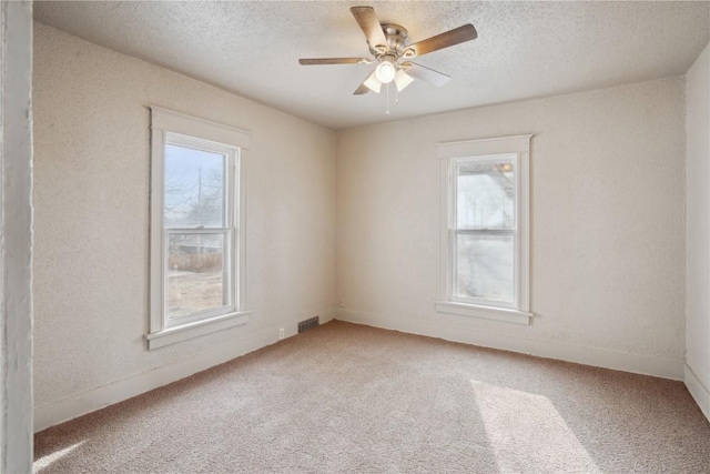 carpeted spare room with ceiling fan and a textured ceiling