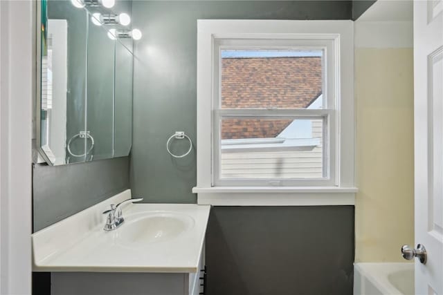 bathroom with a healthy amount of sunlight, a bathing tub, and vanity