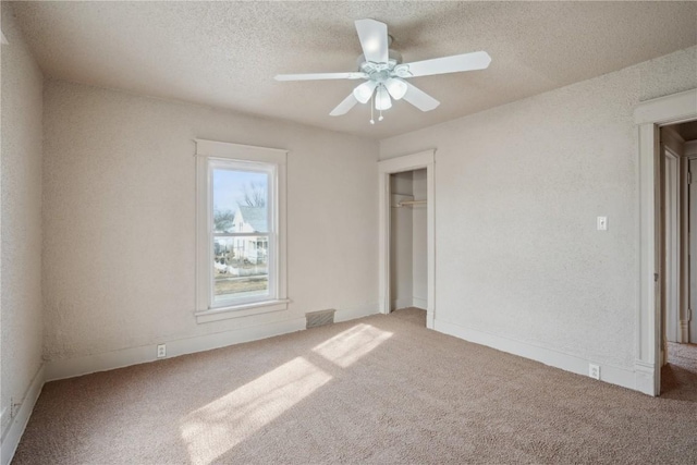 unfurnished bedroom featuring ceiling fan, carpet floors, a textured ceiling, and a closet