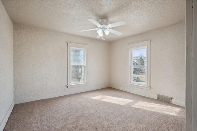 carpeted spare room with a healthy amount of sunlight, a textured ceiling, and ceiling fan