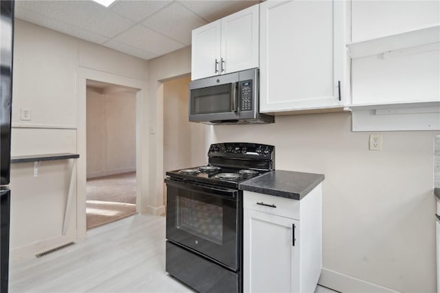 kitchen featuring white cabinetry, black range with electric stovetop, light wood-type flooring, and a drop ceiling